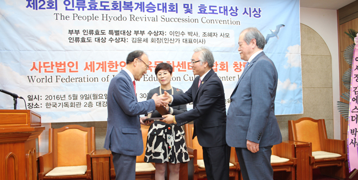 박상원 세계한인재단 상임대표 총회장(오른쪽에서 두 번째)으로부터 공로상을 수상하고 있는 이돈희 위원장(왼쪽).