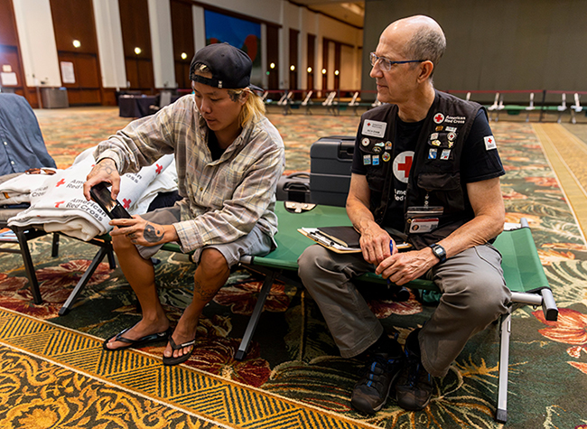 Chris Phillips 씨는 미국 하와이 라하이나에서 발생한 산불을 피해 호놀롤루 소재 하와이 컨벤션센터에 마련된 적십자 임시대피소를 찾아 미국적십자사 직원 Richard Byam 씨와 당시 상황에 대해 대화를 나누고 있다 미국적십자사는 호놀롤루를 비롯한 하와이 내 임시대피소에서 식수 음식 등 구호물품을 이재민에게 지원하고 있다 사진  미국적십자사